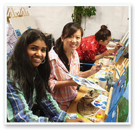 two women smiling holding paint palette and brush while painting in the Heart for Art studio Wellington